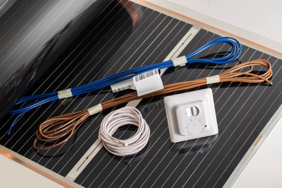 Cables y un termostato sobre una película calefactora negra.