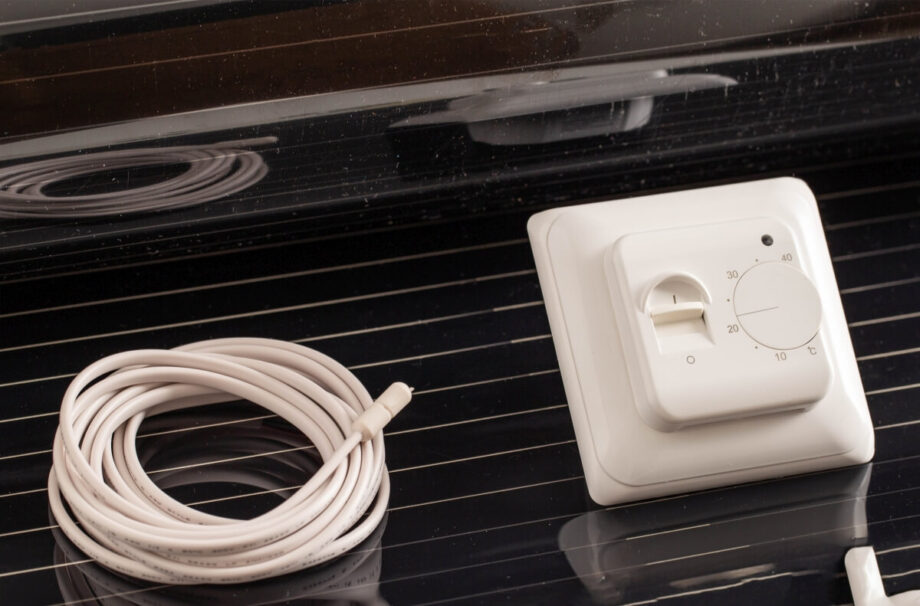 Un termostato y un cable junto a una película calefactora.