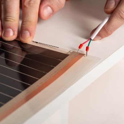 Unas manos instalan un sistema de calefacción por suelo radiante.