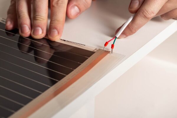 Unas manos instalan un sistema de calefacción por suelo radiante.