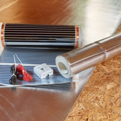 Un folio radiante junto a un rollo de aislamiento térmico y accesorios eléctricos.