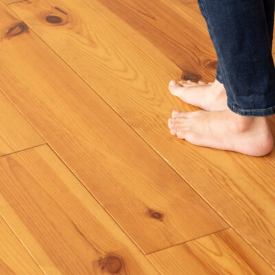 Persona descalza sobre un piso de madera protegido con película para paneles.