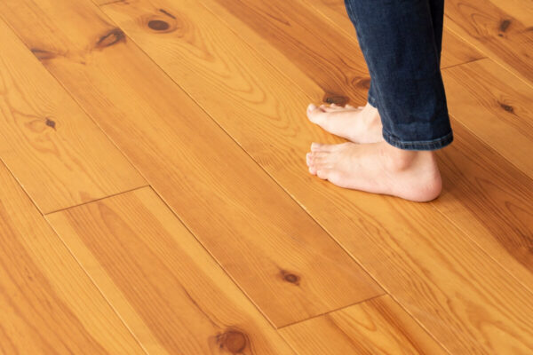 Persona descalza sobre un piso de madera protegido con película para paneles.