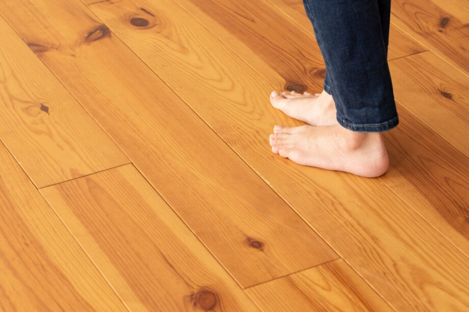 Persona descalza sobre un piso de madera protegido con película para paneles.