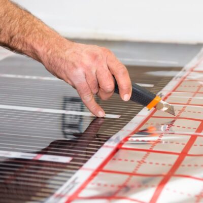 Mano cortando película para paneles con un cúter.