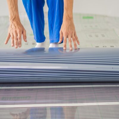 Persona instalando una película calefactora en el suelo.