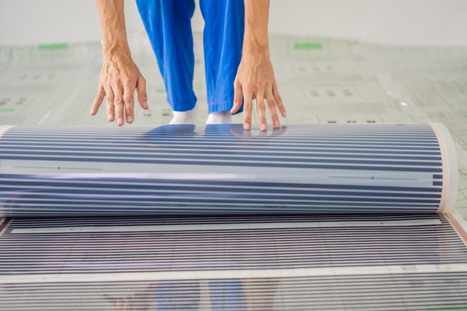 Persona instalando una película calefactora en el suelo.