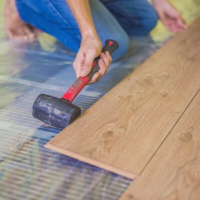 Persona instalando suelo laminado sobre sistema de calefacción por suelo radiante.