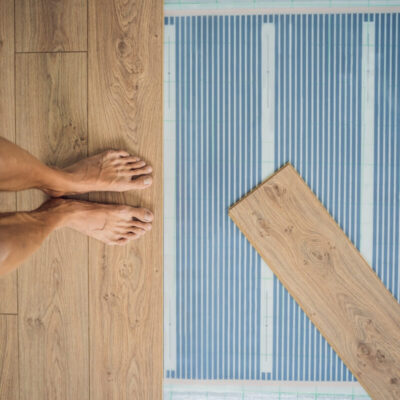 Los pies descalzos de una persona sobre un folio radiante antes de colocar el suelo laminado.