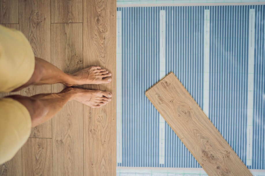 Los pies descalzos de una persona sobre un folio radiante antes de colocar el suelo laminado.